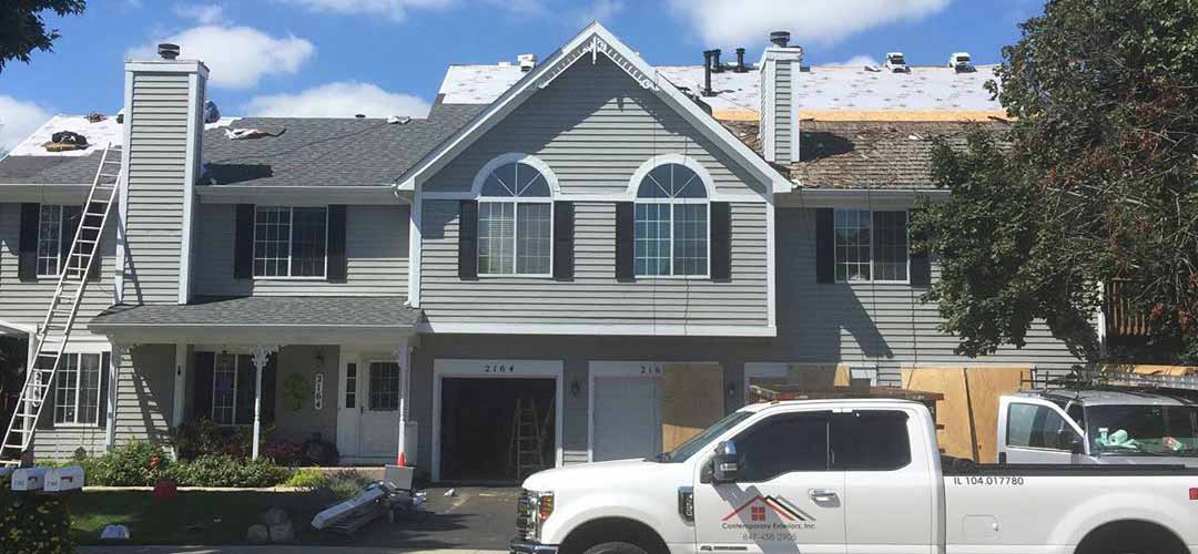 Two-story residential house with grey exterior siding and roof under construction.